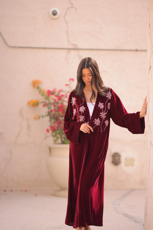 Woman in a burgundy velvet Abaya with floral hand embroidery 