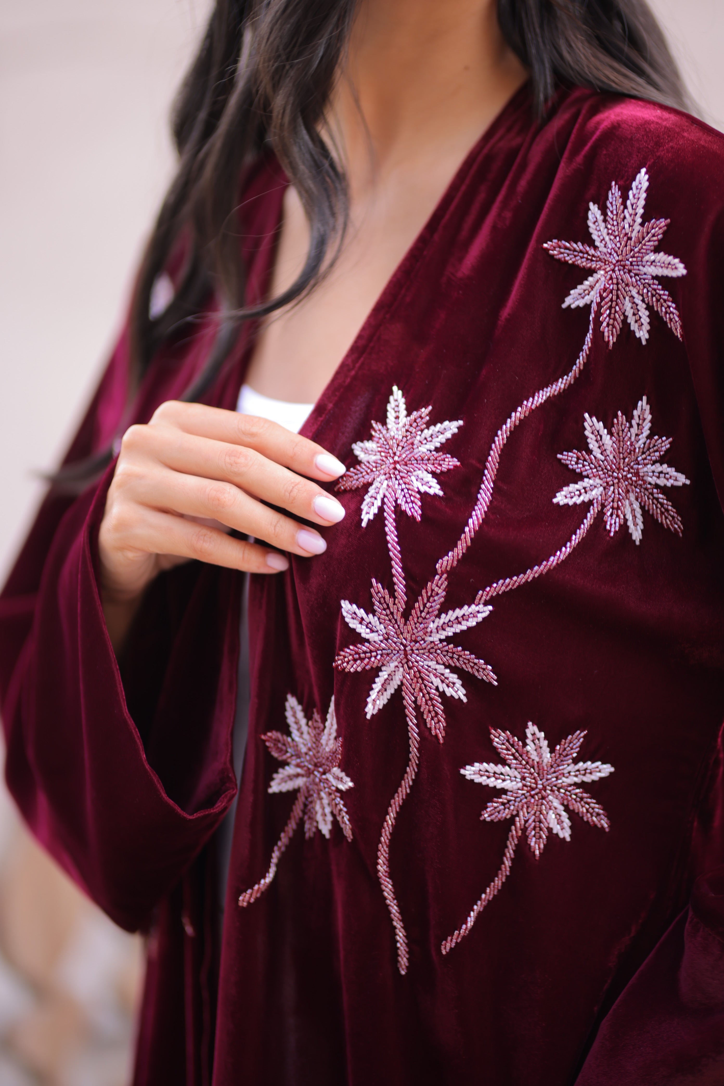 Woman in a burgundy velvet Abaya with floral hand embroidery 