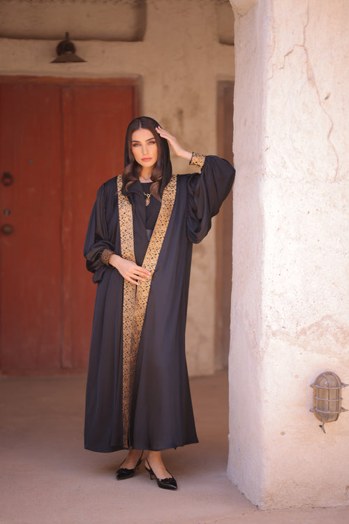 Woman wearing Dark Abaya with Gold trim 