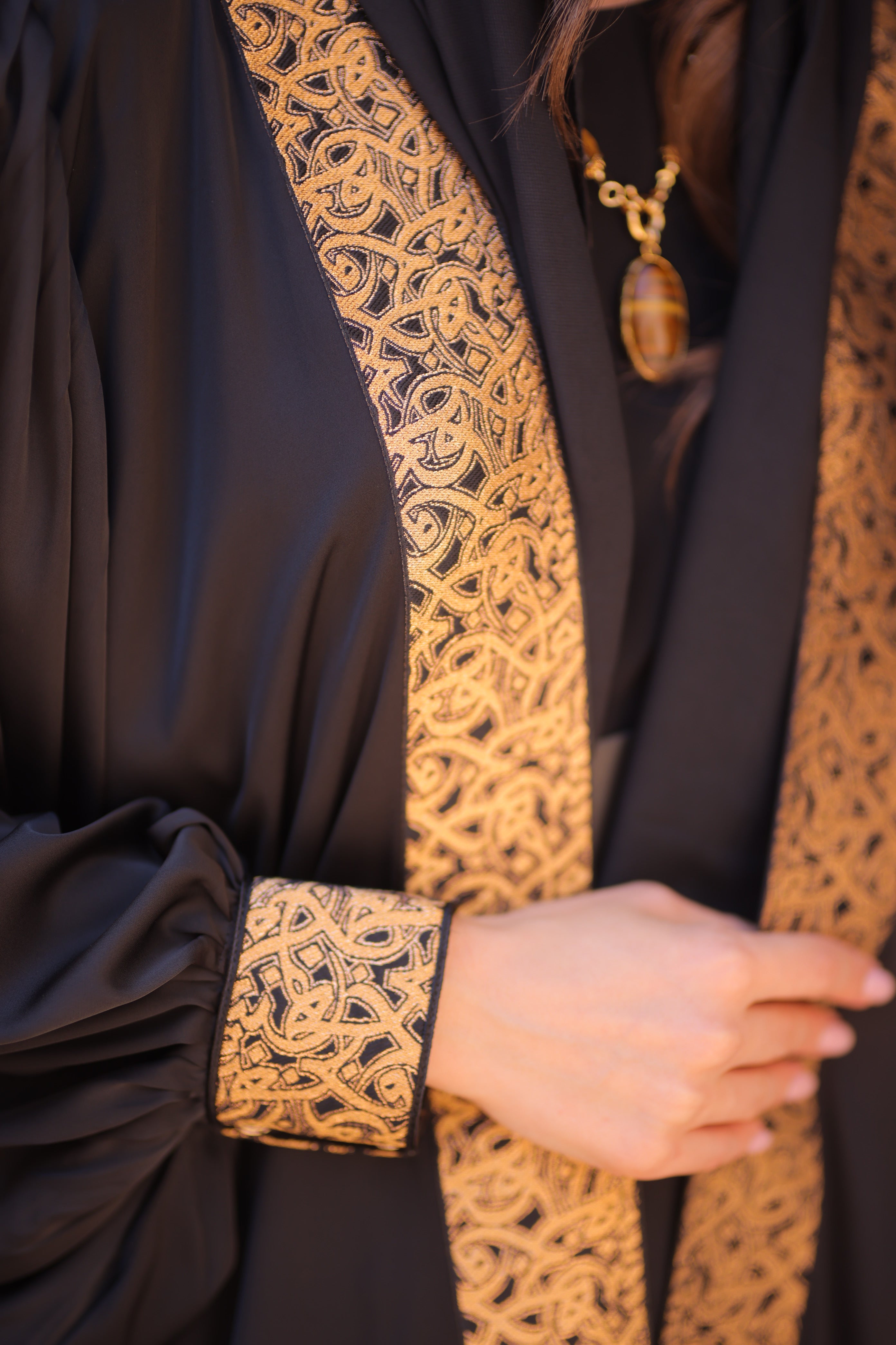 Woman wearing Dark Abaya with Gold trim 