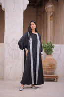 Woman wearing a black abaya with silver trim 