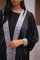 Woman wearing a black  abaya with Silver trim 