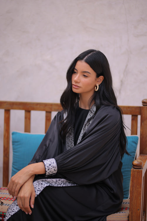 Woman wearing a black dress with silver trim